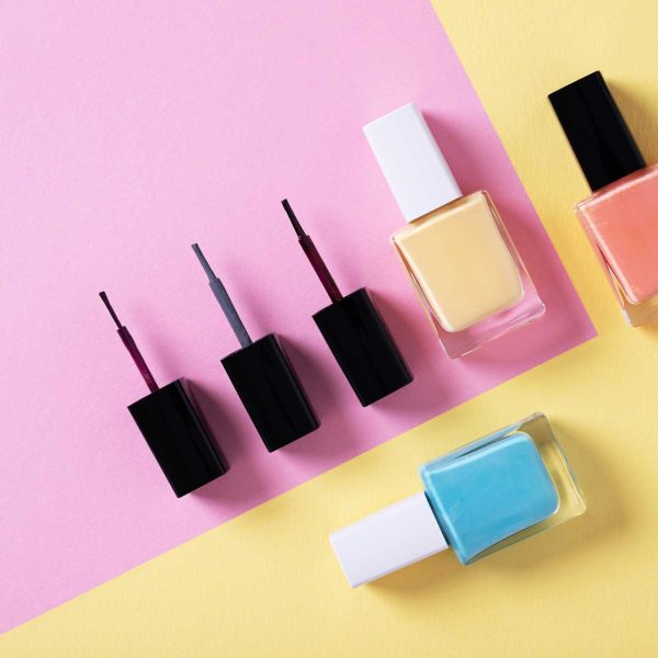 high-angle-shot-of-colorful-nail-polishes-on-multicolor-paper